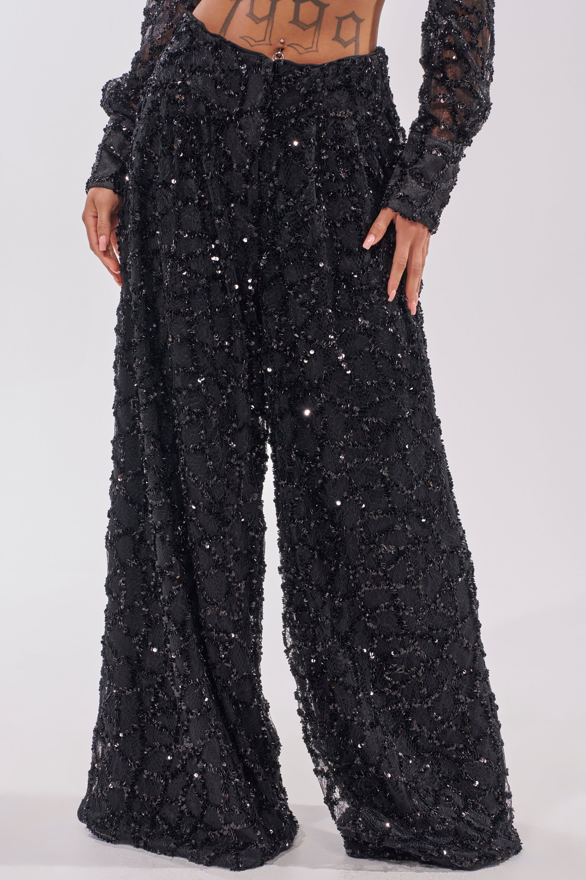 The image shows someone wearing ROXY SEQUIN PALAZZO PANT—high waisted, loose-fitting pants with a textured sequin pattern and wide-leg silhouette. Only the lower torso and legs are visible. 3