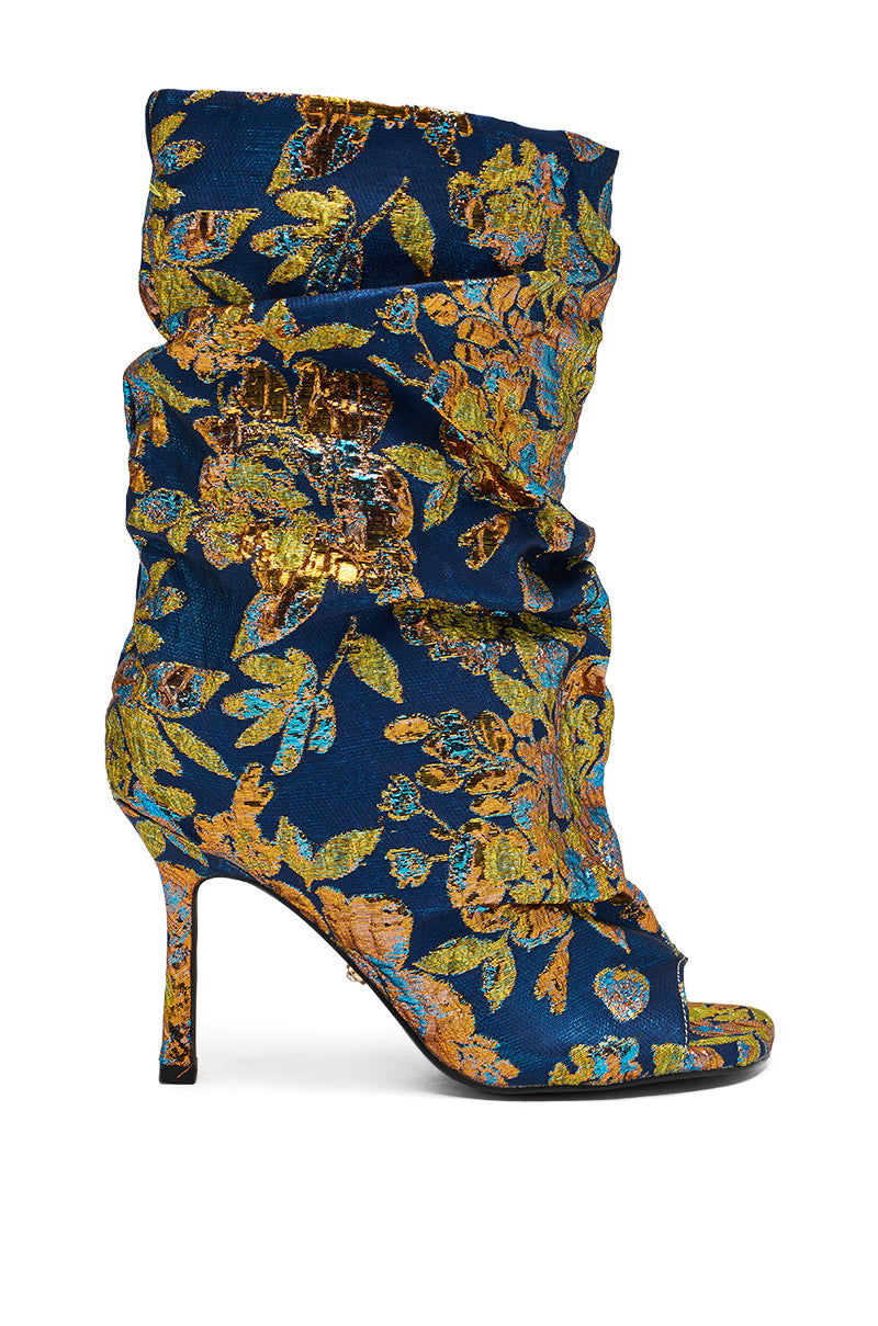 The AZALEA ROZSI BLUE MULTI BROCADE OPEN TOE STILETTO BOOTIE features a high heel, slouchy silhouette, and rich blue fabric with intricate gold and bronze florals for a striking metallic brocade effect.
