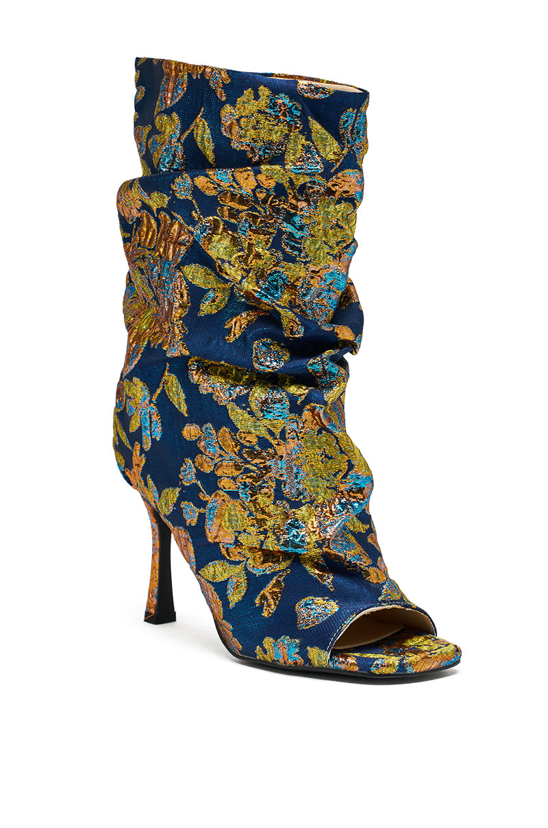The AZALEA ROZSI BLUE MULTI BROCADE OPEN TOE STILETO BOOTIE features blue satin with gold, green, and turquoise floral patterns and a slouchy ankle design—an elegant update to the classic stiletto bootie.