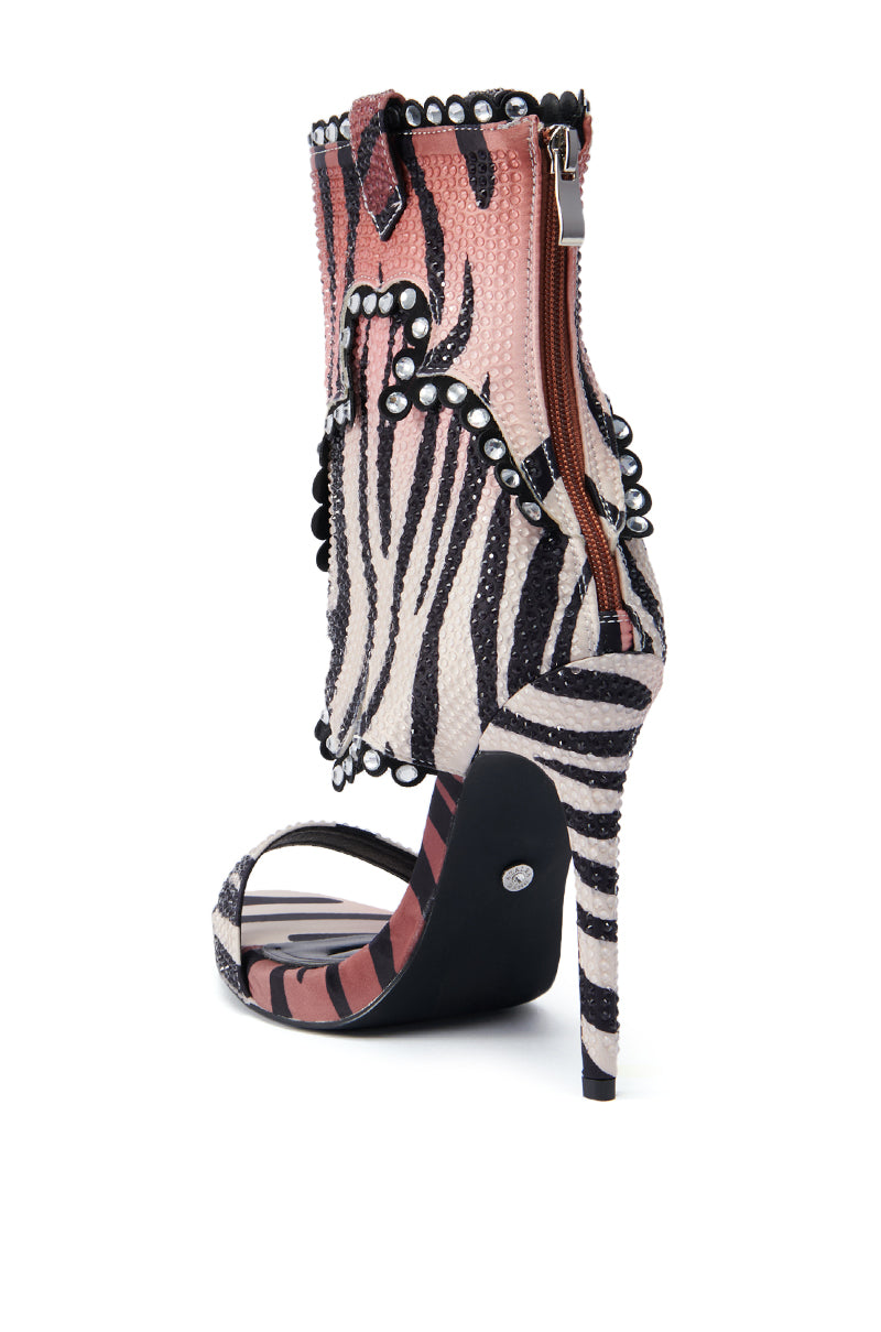 The AZALEA WANG RUMMIE TIGER STILETTO SANDAL is a high-heeled shoe showcasing a zebra print design with black and white stripes, enhanced by pink accents and rhinestone embellishments. Small black circular decorations adorn the ankle area, while a side zipper adds functionality. This open-toe style is completed with a slim heel for an elegant appearance.