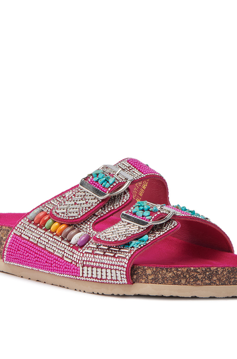 The AKIRA RUVY FUCHSIA STONE EMBELLISHED FLAT SANDAL features a cork sole, two adjustable silver buckles, pink beaded straps with turquoise accents, metallic details, and sparkling rhinestone embellishments.