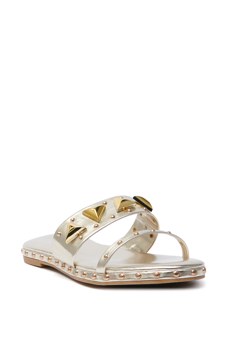 The AKIRA RYLIE Gold Embellished Slip-On Sandal exudes elegance with a silver metallic faux leather design. Featuring two straps adorned with gold pyramid-shaped studs and small round studs along the edge, it offers a chic flat sole and open toe perfect for any occasion.