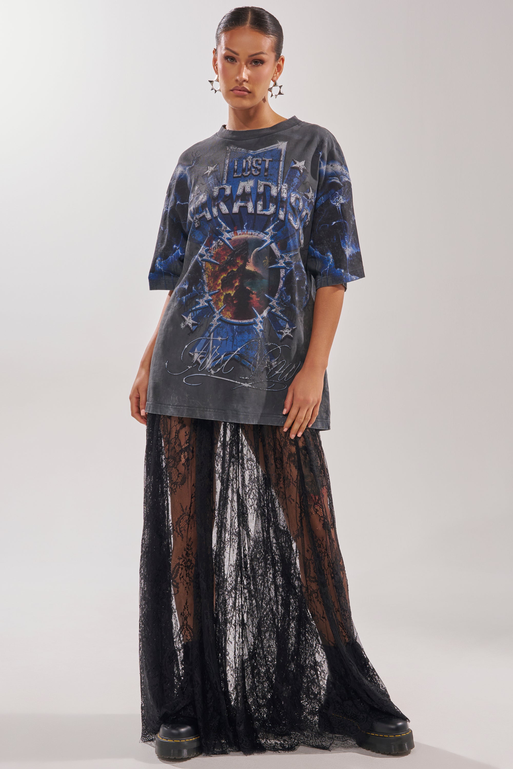 A woman in a loose "Lost Paradise" graphic tee, layered over the LOVELY DAYS LACE MAXI SKIRT and black platform shoes, stands against a plain light background—a bold twist on contemporary resort wear. 4