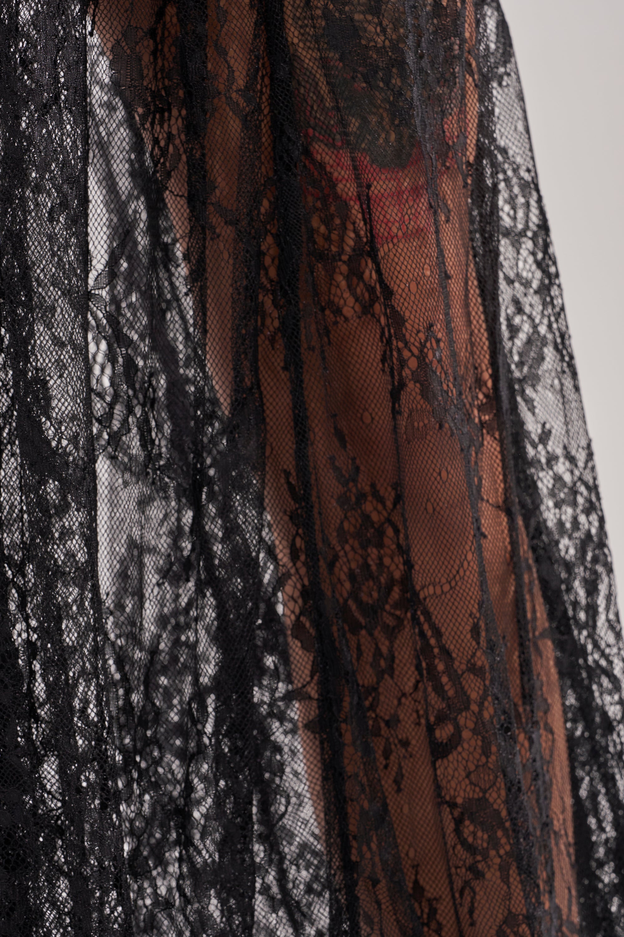 The LOVELY DAYS LACE MAXI SKIRT is a sheer black maxi skirt with delicate floral lace, draped to reveal skin and subtle hints of pink clothing—an ideal choice for chic resort wear. 8