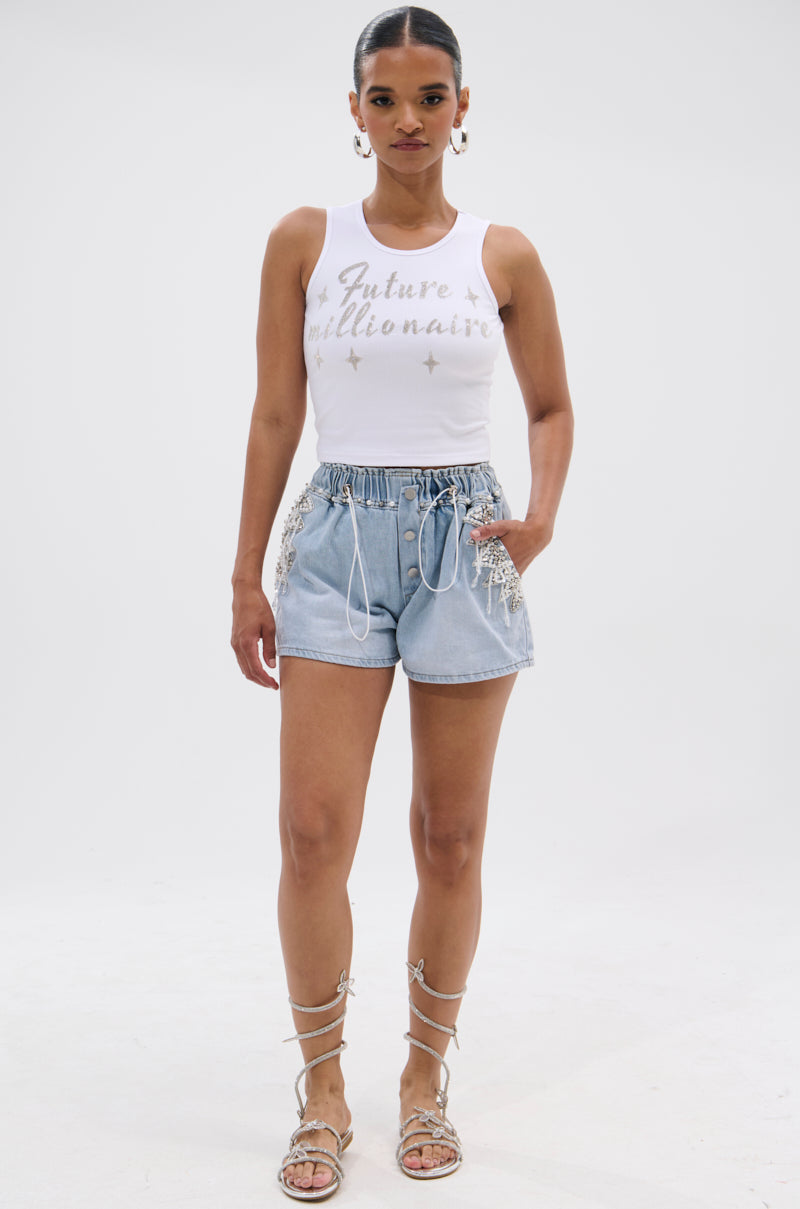 A woman stands facing forward, wearing a white sleeveless "Future millionaire" top, BLING BLING PEARL DENIM SHORTS in light blue with lace details, and silver lace-up sandals against a white background. 5