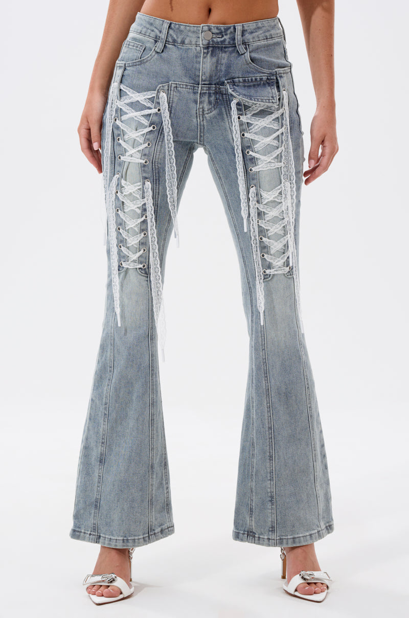 A person wears TIED UP FLARE JEANS—high-waisted, light-wash flares with bold white lace-up front detailing—paired with open-toe white heels against a plain white background. 4