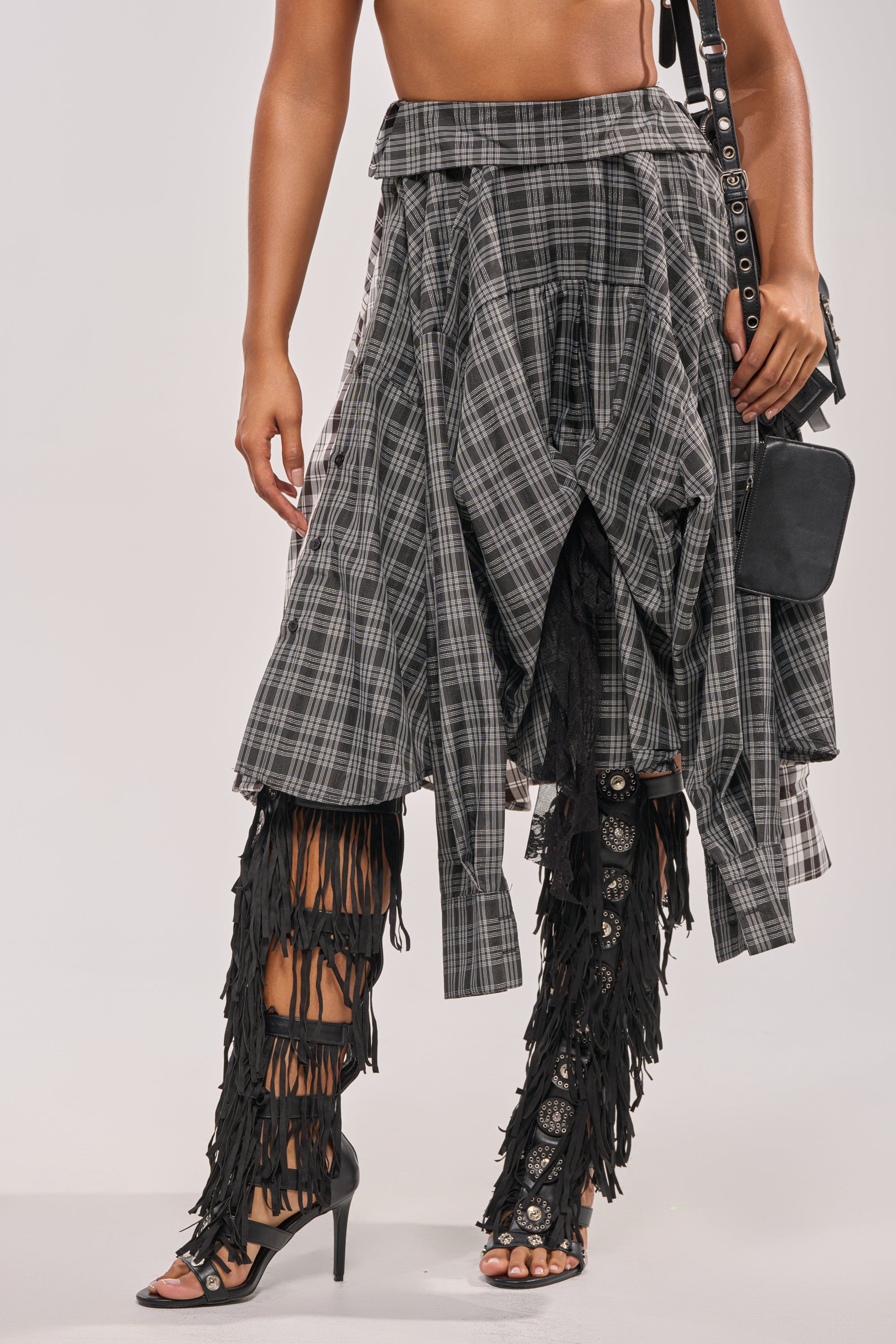 Wearing the FALL VIBES PLAID MIDI SKIRT with a black fringed bag and black open-toe heeled sandals featuring fringe up the legs, this modern, edgy look stands out. 4