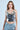 A woman stands against a simple backdrop, wearing the party-ready BLING BLING TOP paired with light blue jeans. Her hair falls freely, decorated with long earrings. She exudes confidence as the sequin discs of her top shimmer brilliantly.