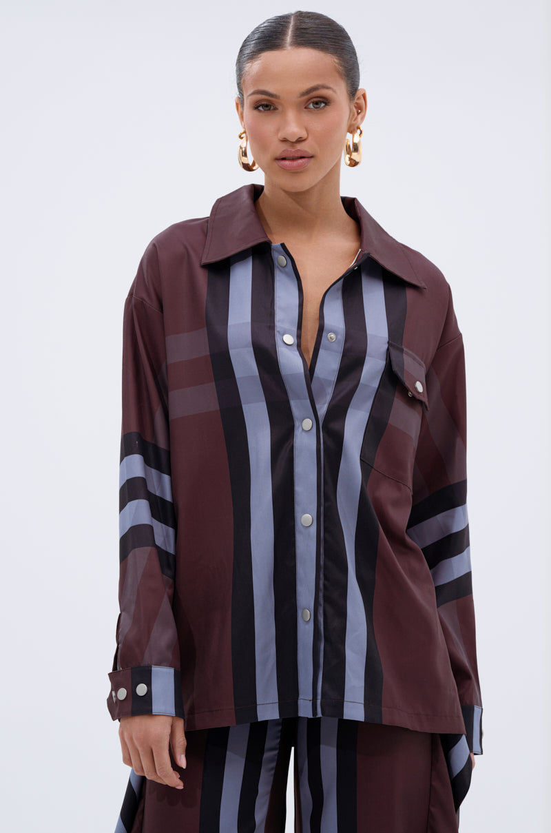 A woman with slicked-back hair and gold hoop earrings wears the LUXURY LIFE PLAID BUTTON DOWN shirt and matching pants, standing against a plain light background.