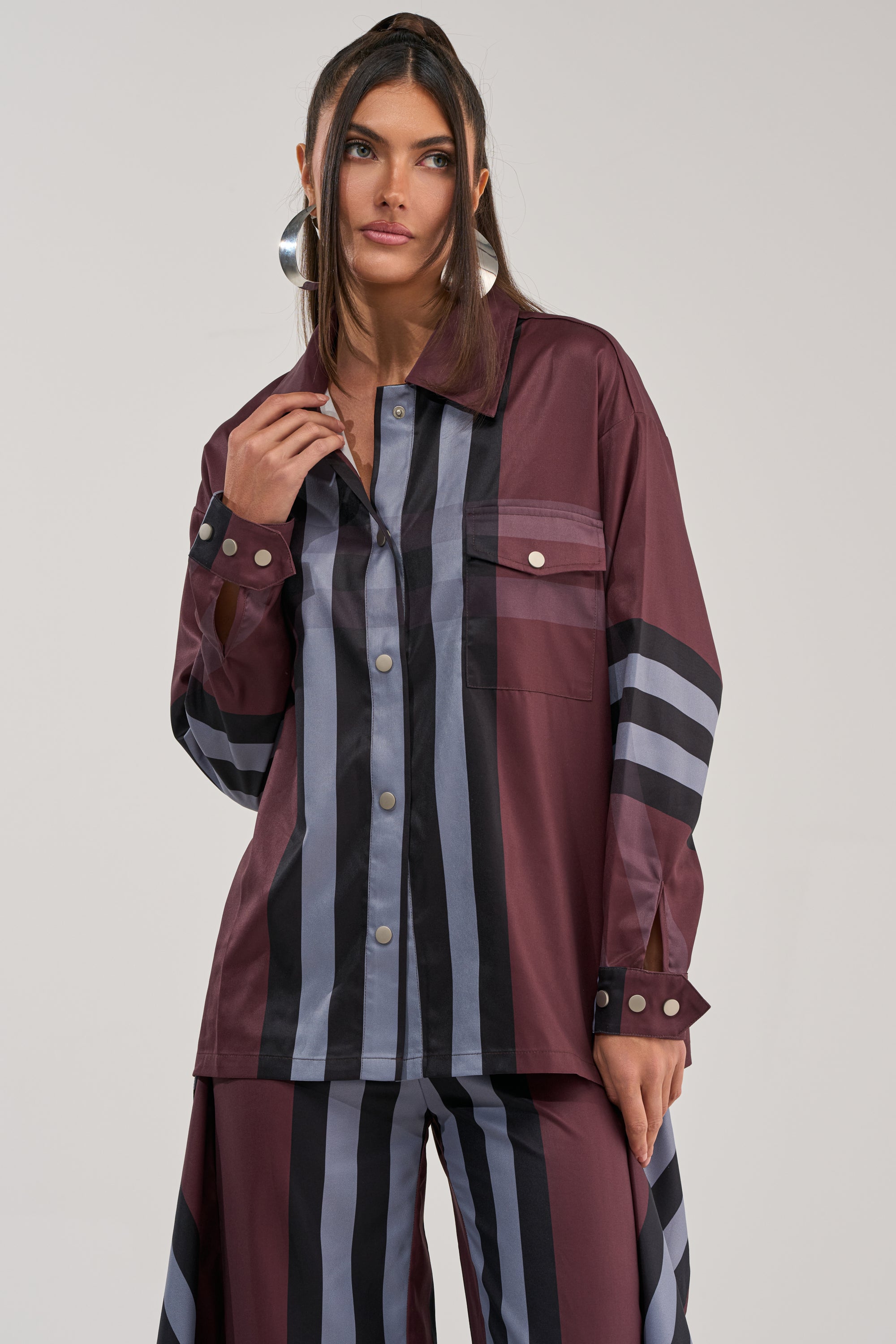 A woman with long dark hair wears the LUXURY LIFE PLAID BUTTON DOWN and matching wide-leg pants, creating a relaxed silhouette as she stands against a plain light background.