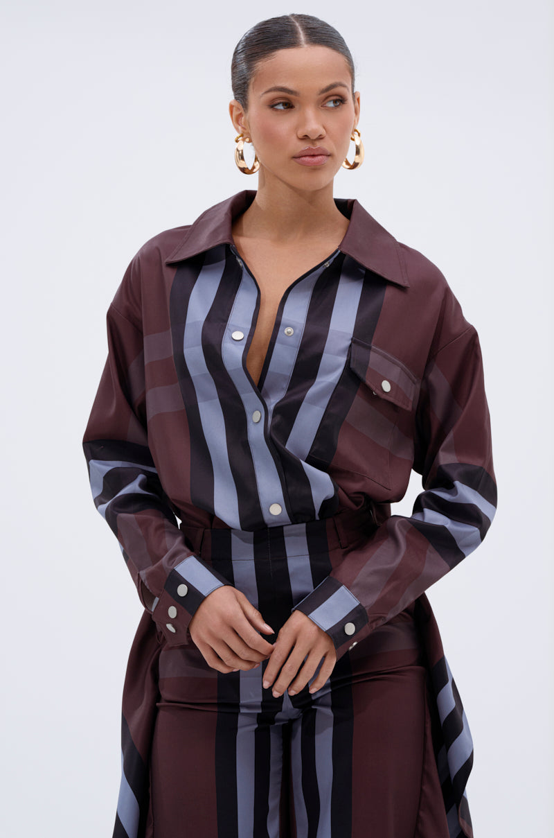 A woman wearing the LUXURY LIFE PLAID BUTTON DOWN with matching pants, gold hoop earrings, and her hair pulled back stands against a plain light background.