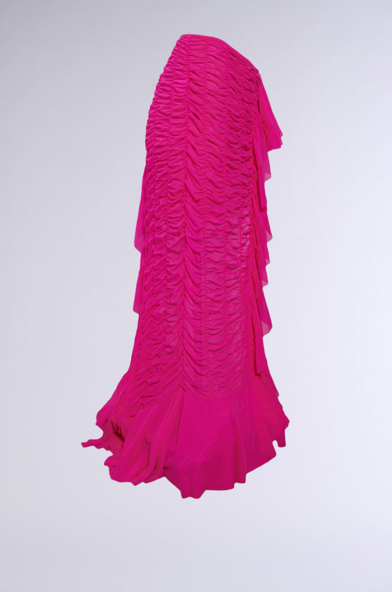 The LAYERED UP MESH RUFFLE BELT SKIRT is a vibrant pink, floor-length skirt with textured mesh, ruched details, and flowing side ruffles, ideal for festival fashion and shown against a plain light background.