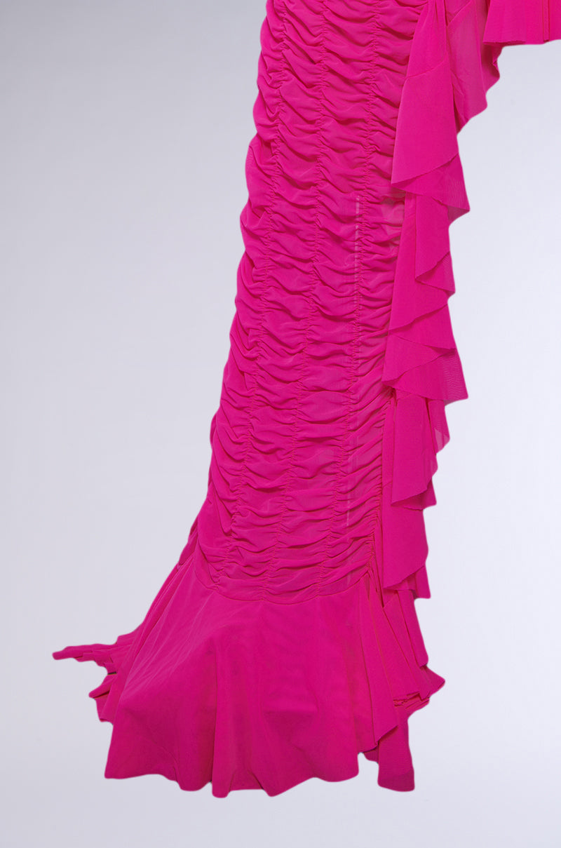 A close-up of the LAYERED UP MESH RUFFLE BELT SKIRT, showcasing vibrant pink mesh layers, ruched fabric, ruffle details, and a flared hem—ideal for festival fashion—set against a light gray background.