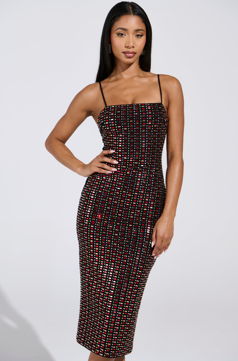 Wearing the RENEE RHINESTONE MIDI DRESS, a person poses with one hand on their hip against a plain backdrop. The sleeveless, knee-length bodycon fit dress features a grid pattern of red and silver rectangles. Their long, straight black hair flows effortlessly.