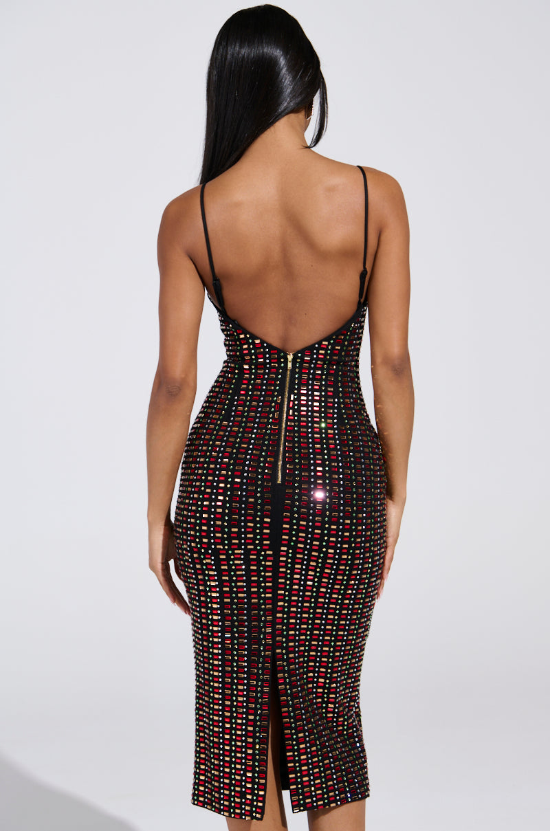 A woman with long black hair, back to camera, dons the RENEE RHINESTONE MIDI DRESS. This sleeveless, backless cotton-blend piece is adorned with red and silver sequin vertical stripes. Featuring thin straps and a calf-length hem with a back slit, it offers an elegant bodycon fit.