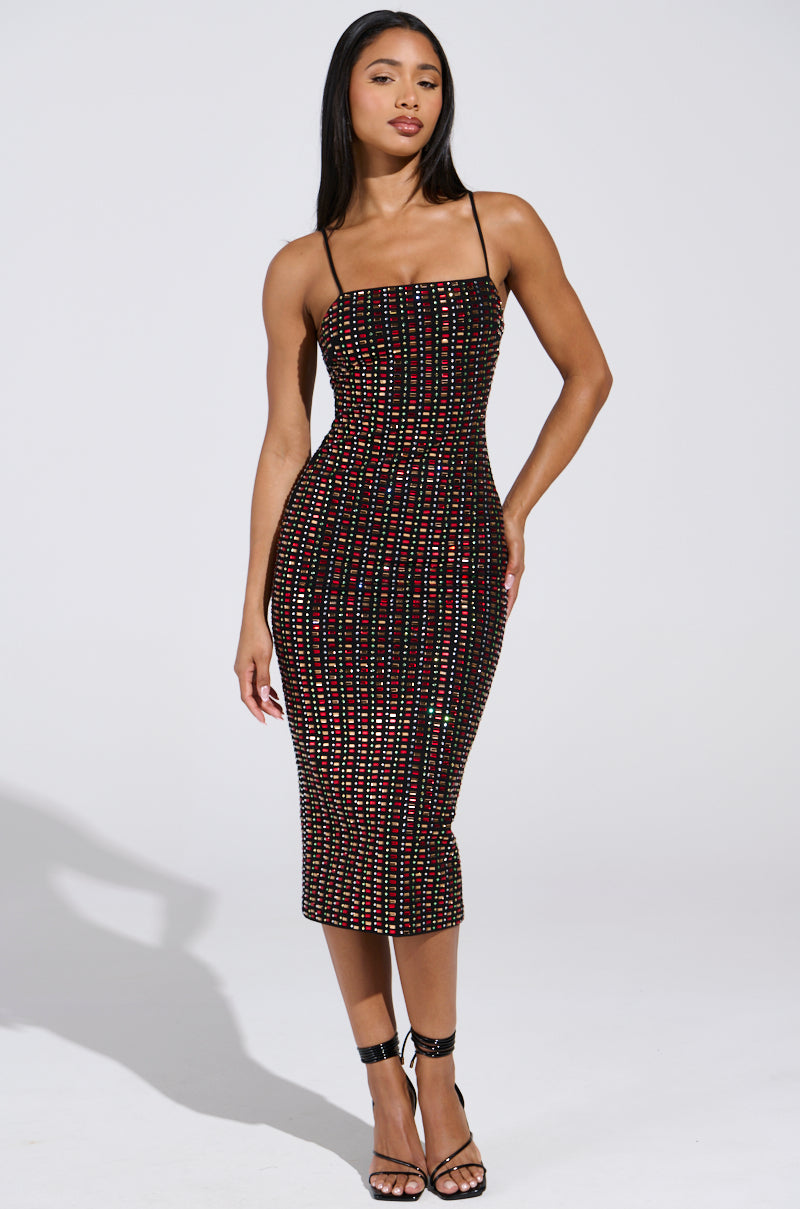 A person models the RENEE RHINESTONE MIDI DRESS, a fitted sleeveless cotton-blend midi with multicolored bead rows and thin straps. They pair it with strappy black heels against a plain white backdrop.