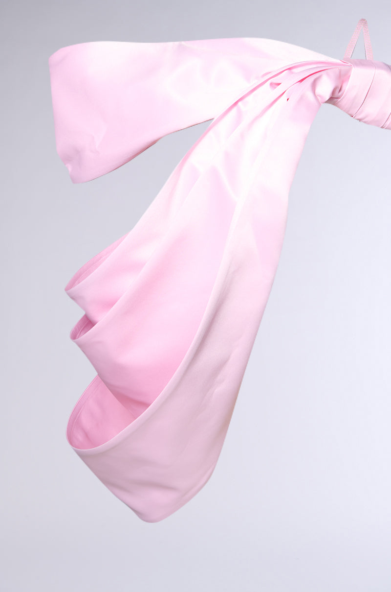 A close-up of the IM THE GIFT BODY ACCESSORY, crafted from luxe satin and tied in a loose knot against a plain, light gray background—a chic and stylish fashion statement.