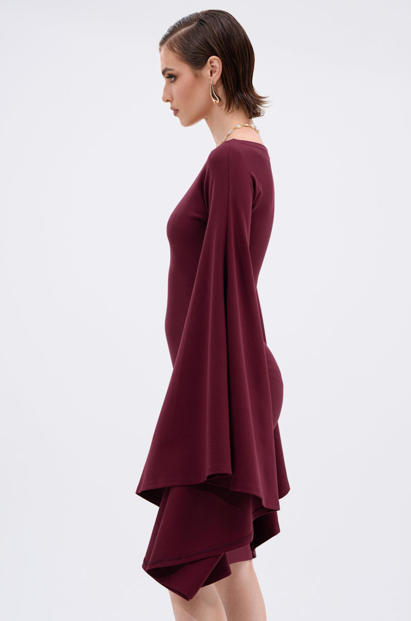 A woman in profile showcases the MEET ME IN THE BALLROOM MIDI DRESS IN BURGUNDY, featuring a fitted silhouette, long dramatic bell sleeves, and an asymmetric hem—ideal for formal events. She accessorizes with gold hoops and a necklace.