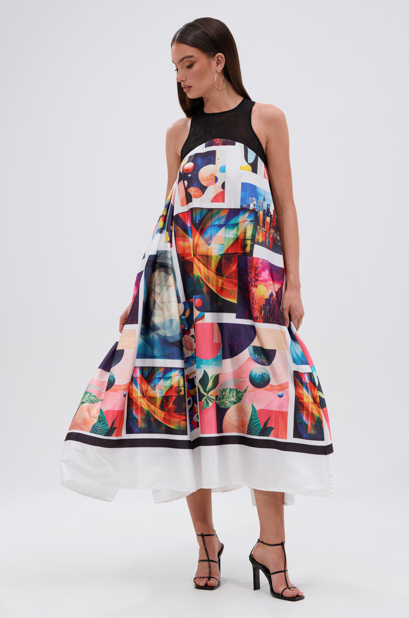 A woman in the PUT ME IN A MUSEUM PRINTED MIDI DRESS, a sleeveless midi with a high neck and flared skirt, features AKIRA Label’s bold abstract prints. She stands against a plain light background, looking down.