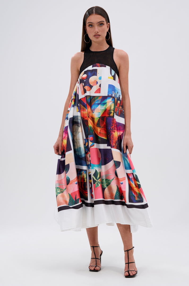 A woman wearing the PUT ME IN A MUSEUM PRINTED MIDI DRESS with abstract graphic prints on the skirt stands against a white background. She has long brown hair, hoop earrings, and black strappy heels.