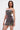 A person stands confidently in the ISLAND GIRL PRINTED MINI DRESS, its fitted, sleeveless cut and thin straps evoking a tropical vibe. With long straight hair and a small handbag, they look to the side against a plain background.