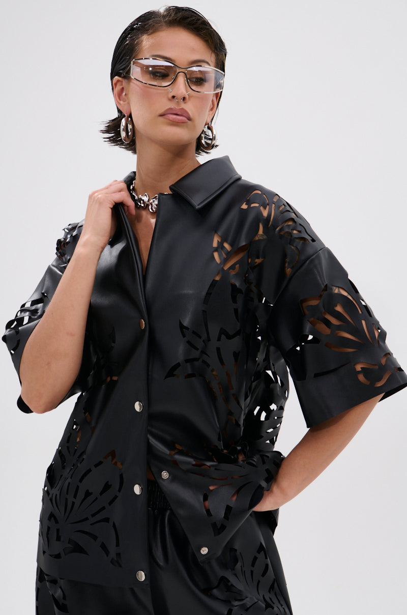 Wearing the GOING CRAZY PU CUTOUT BUTTON DOWN TOP, silver hoop earrings, a chunky chain necklace, and clear futuristic sunglasses, a person poses confidently against a plain background.