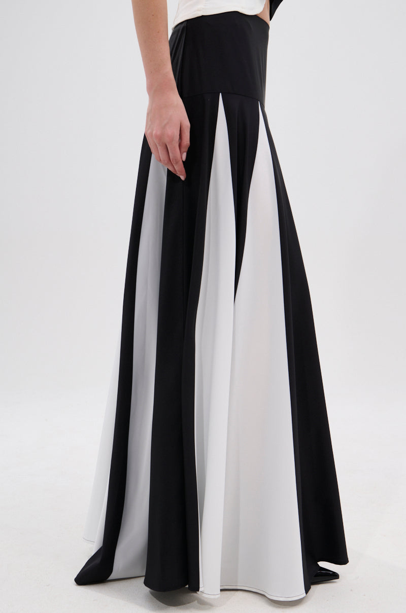 A person showcases the lower body in the RACHEL SATIN MAXI SKIRT, featuring alternating black and white vertical panels and a high-rise waistband, posed against a plain white background. 4