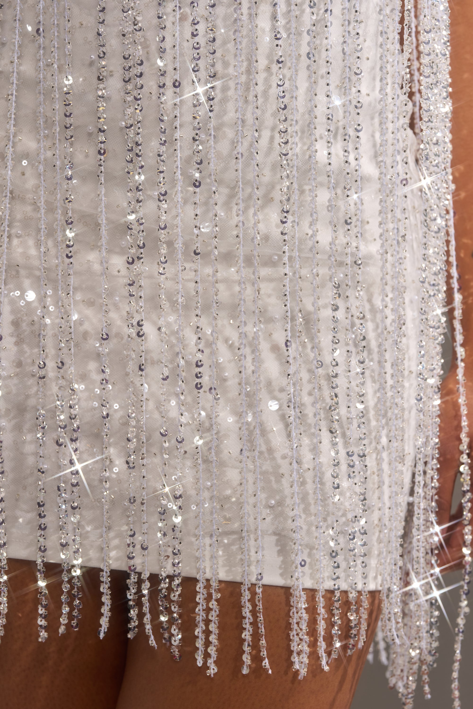 Close-up of the CAME THRU DRIPPIN' FRINGE MINI DRESS, featuring white sequin fringe and beaded tassels that shimmer in the light for a striking, glamorous effect.