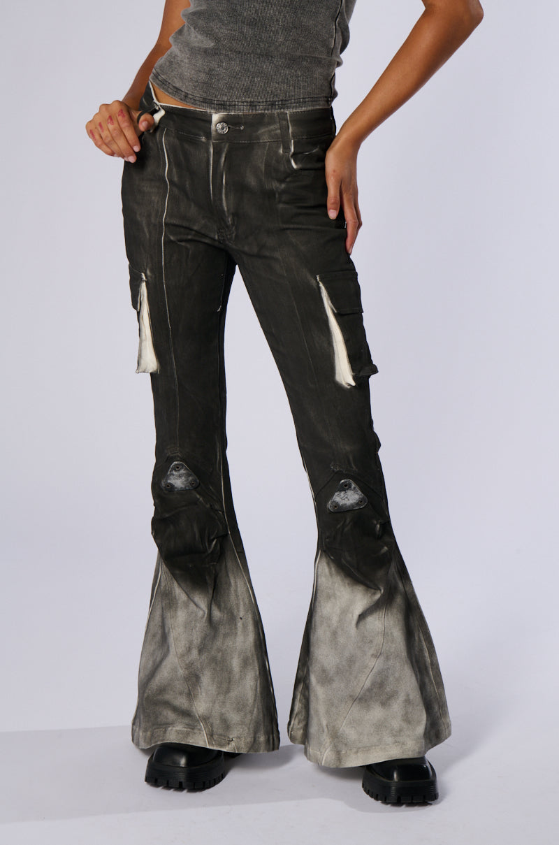 A person wearing dark gray flared pants with a distressed look and two front tassels, styled similarly to the ROCK YOU ALL NIGHT LONG DENIM PANT, paired with a matching dark gray top. The outfit is completed with black chunky platform boots against a plain white background.