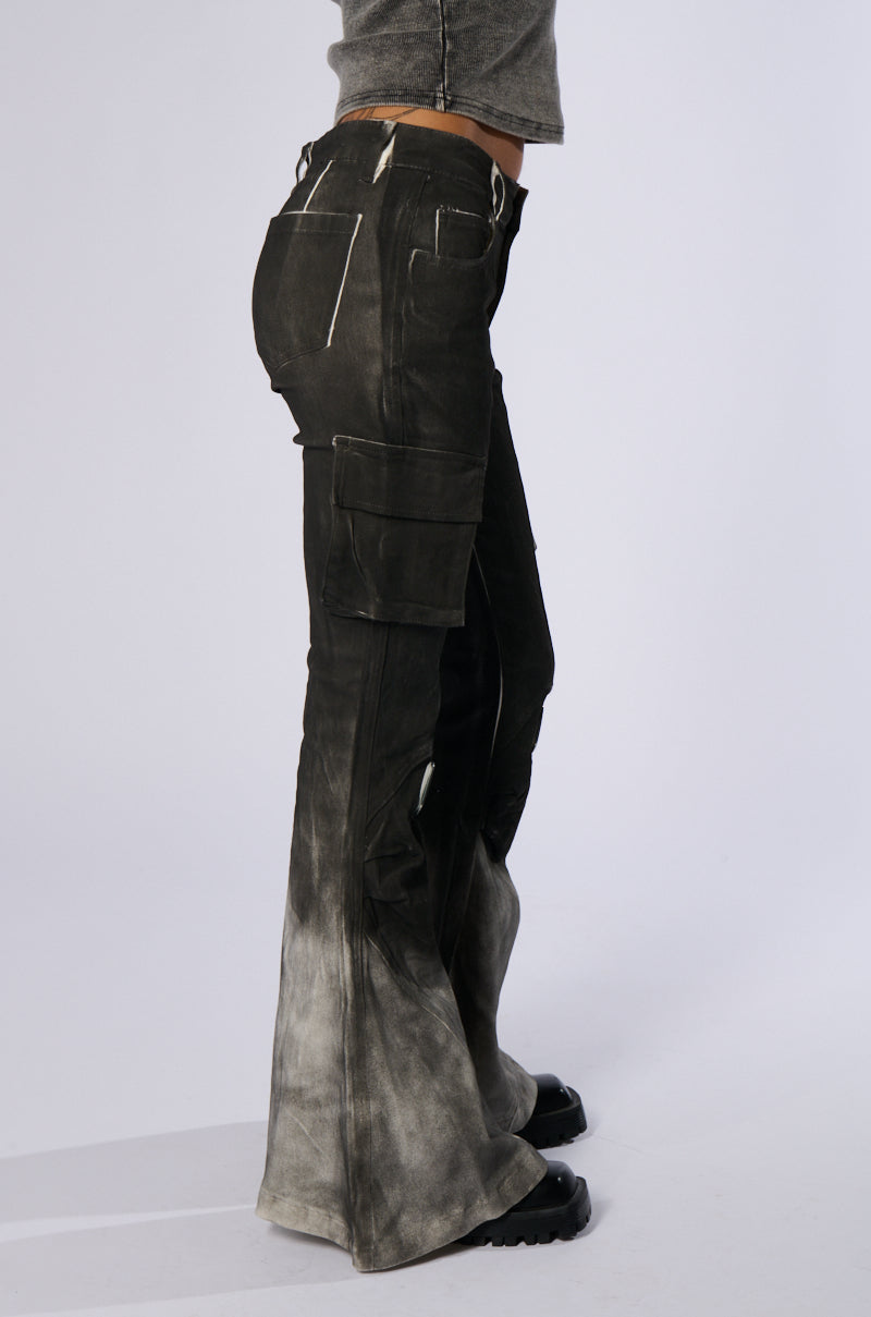 A person wearing dark, high-waisted ROCK YOU ALL NIGHT LONG DENIM PANTS that fade to a lighter color at the bottom. The pants feature multiple pockets and an artsy airbrushed design, paired with a cropped, long-sleeve shirt. The person is standing in profile view, showcasing the side of the outfit against a plain background.