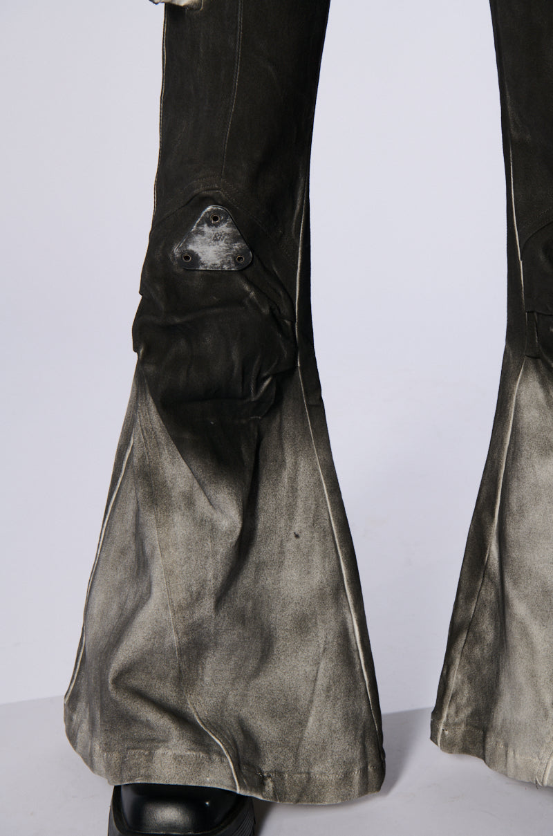 Close-up of the lower legs of a pair of ROCK YOU ALL NIGHT LONG DENIM PANTS, showcasing an artsy airbrushed design with some fraying and repair patches. These dark, distressed flare pants have a high-rise fit 'n flare silhouette that gradually becomes lighter towards the hem, paired with black footwear.