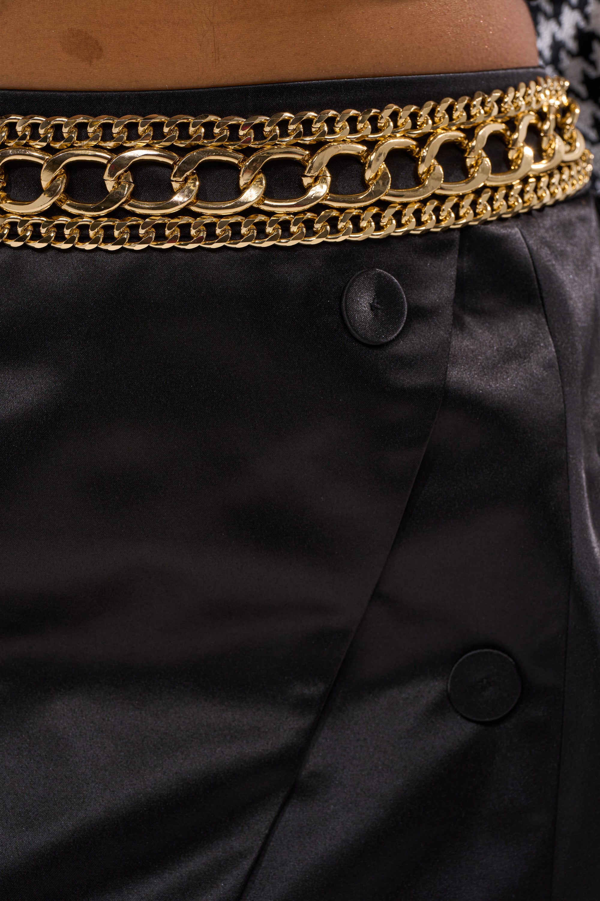 Close-up of a person wearing the ALL FOR IT MINI SKIRT, featuring a sculpted silhouette, large buttons, and a chunky gold chain belt at the waist. 13