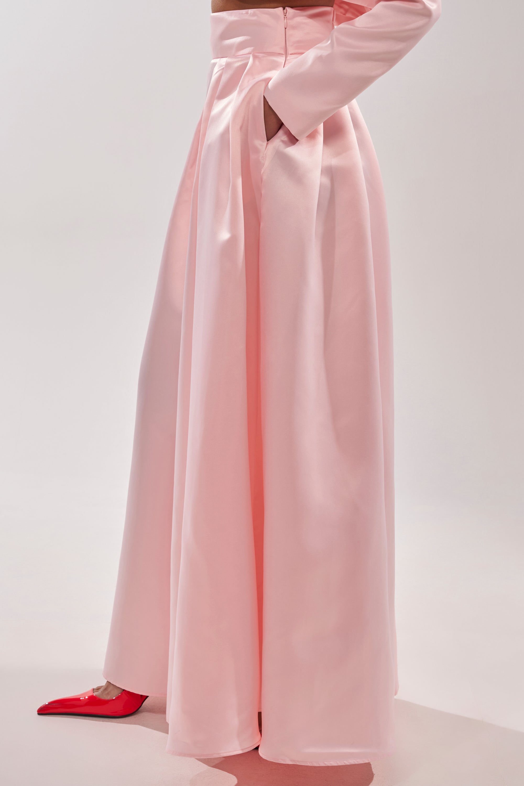 A person wearing the LILA SATIN WIDE LEG PANT in pale pink with a matching long-sleeve top and pointed red shoes stands against a light background. 4