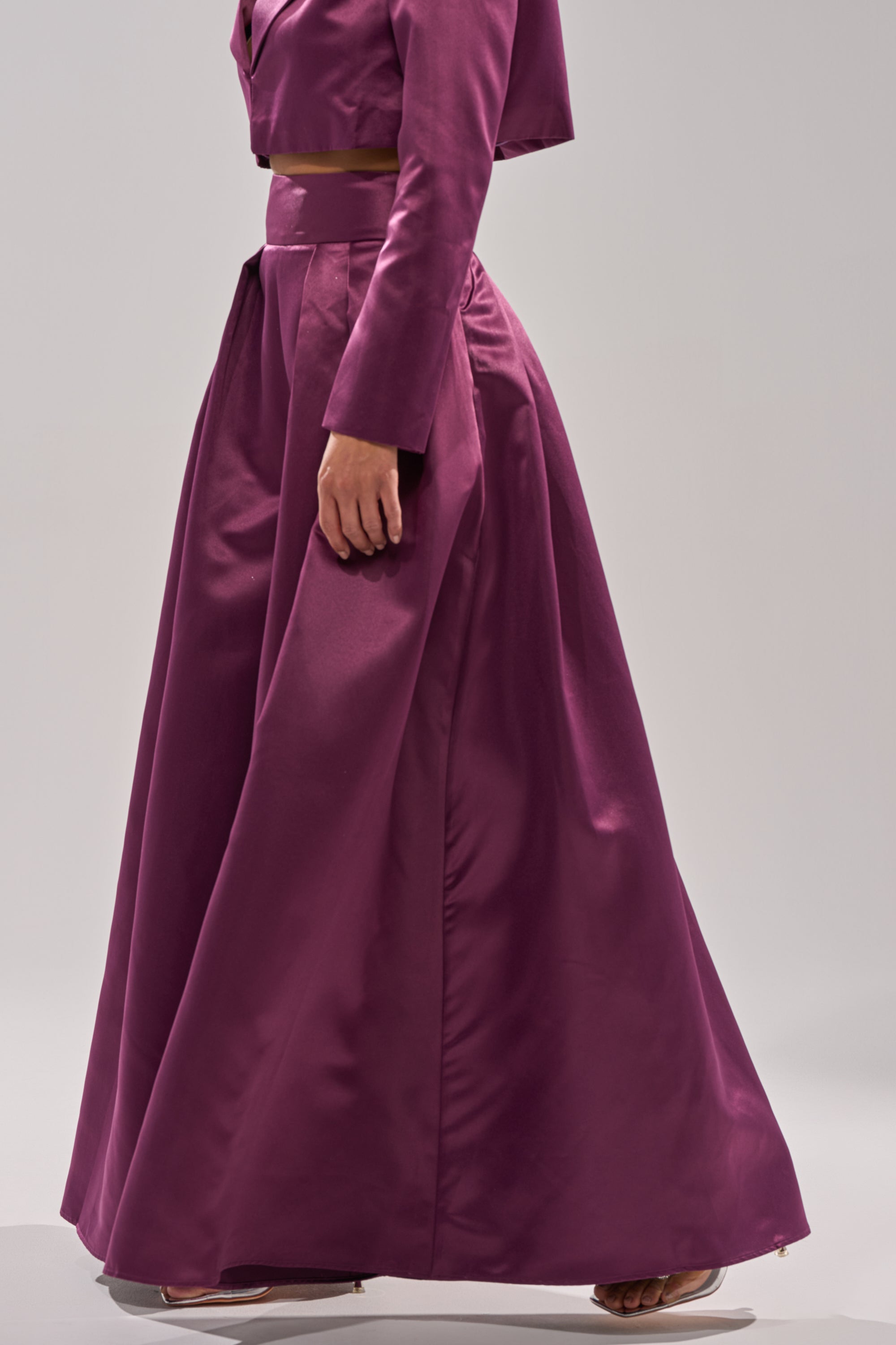 A person wearing ON AND ON WIDE LEG TROUSER in magenta, paired with a matching high-rise cropped jacket, stands sideways against a plain light background, showing only the lower face and body.