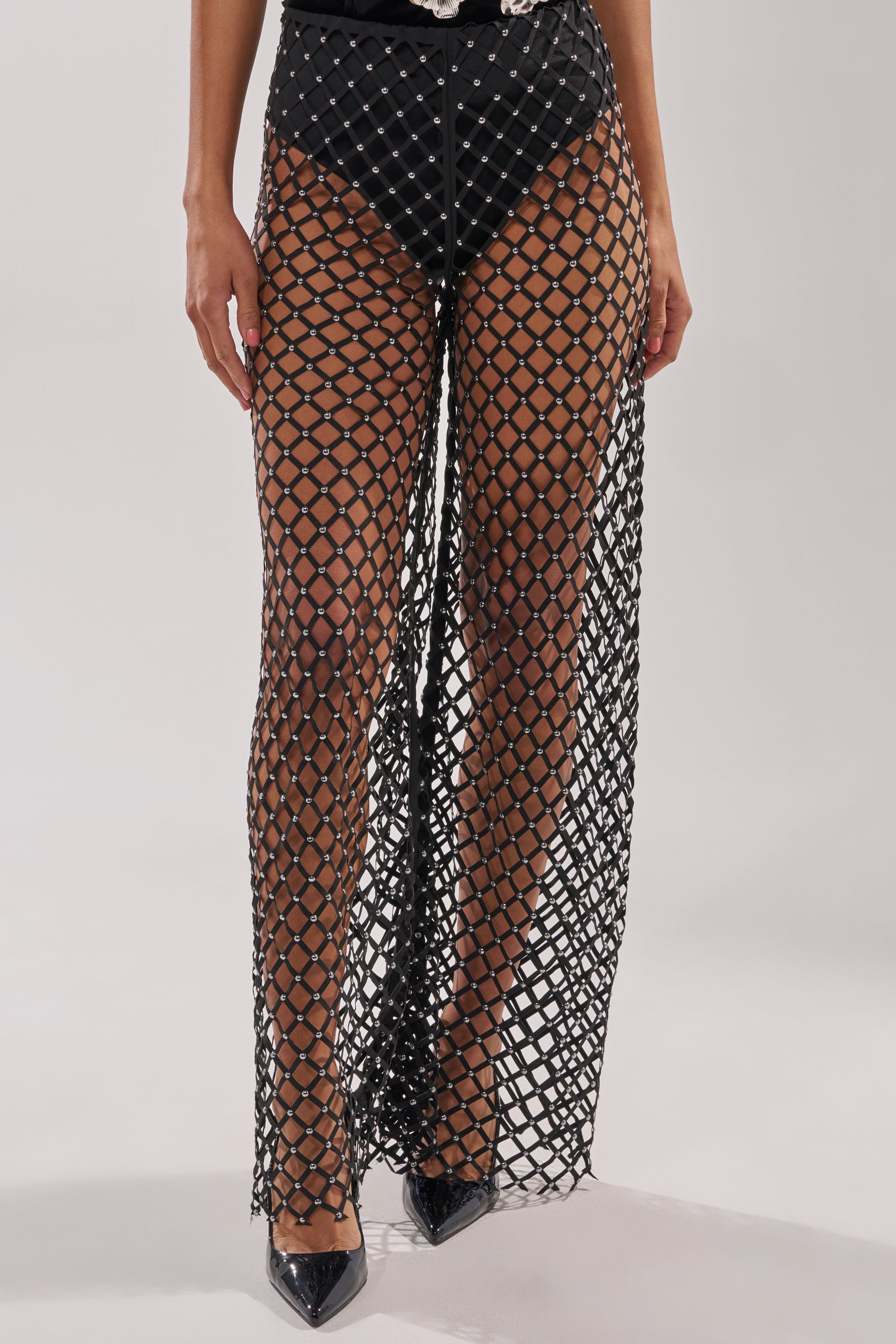 A person wearing black high heels, black briefs, and the CELINE STUD MESH PANT—a long, sheer rhinestone mesh skirt with a diamond pattern. The photo is cropped from the waist down. 2