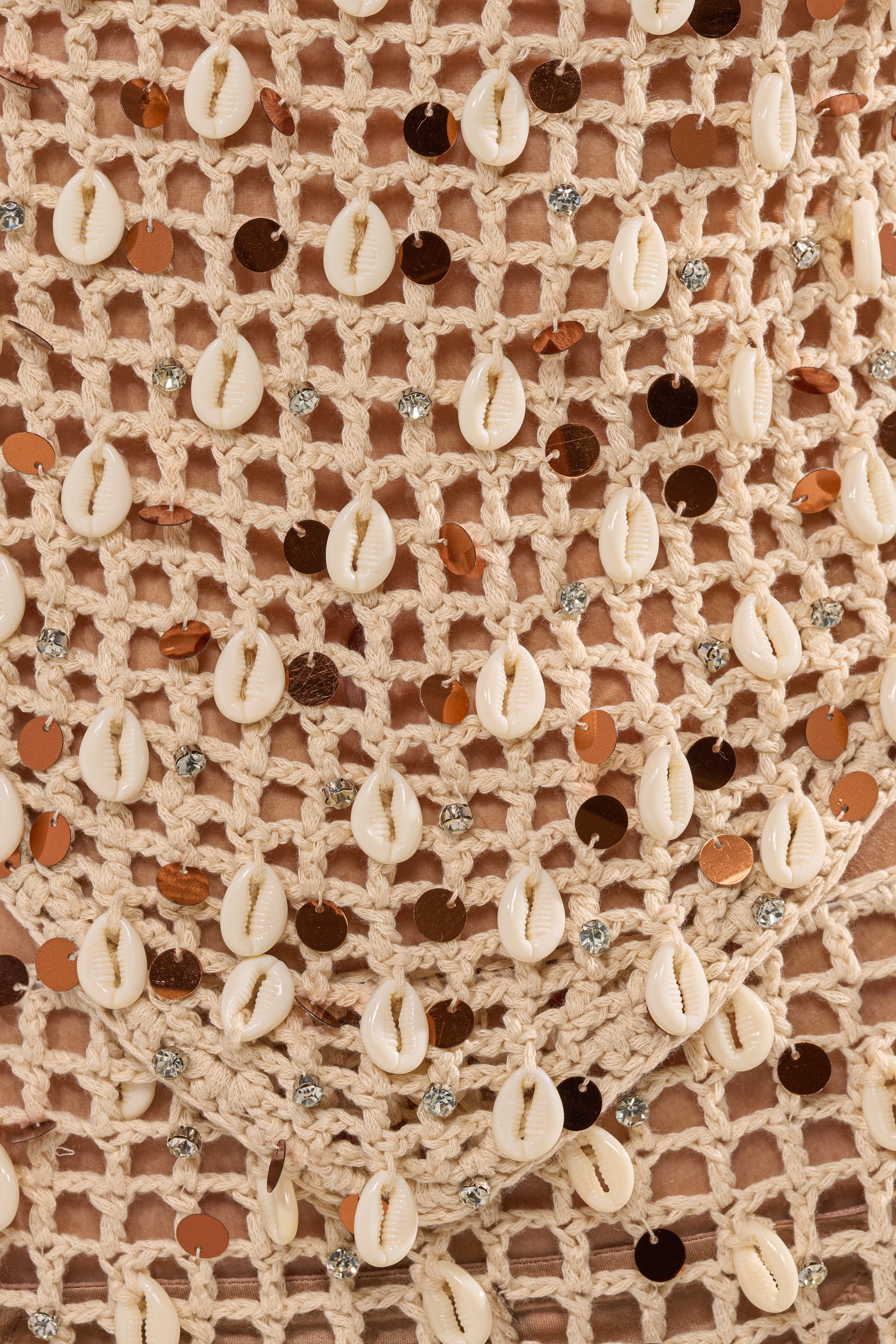 Close-up of the SEASHELL CROCHET MINI SKIRT, featuring a detailed pattern with white cowrie shells, shiny brown sequins, and small silver beads for a textured, elegant look. 8