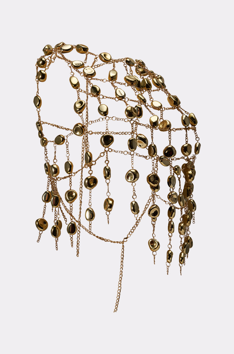The PEBBLE BEACH STONE CHAIN TOP features elegant gold chains with shiny, oval pebble charms draped asymmetrically over a mannequin shoulder—an eye-catching statement piece styled against a plain light background. 10