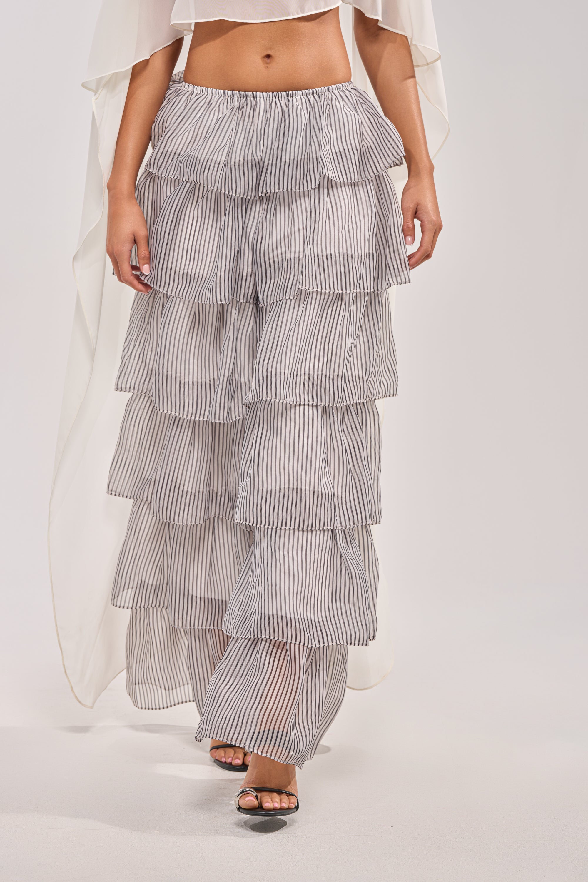 The lower half of a person is shown wearing black sandals and the ALL I WANT TO DO STRIPE PALAZZO PANT, featuring thin vertical black and white stripes—an ideal spring styling choice. 1