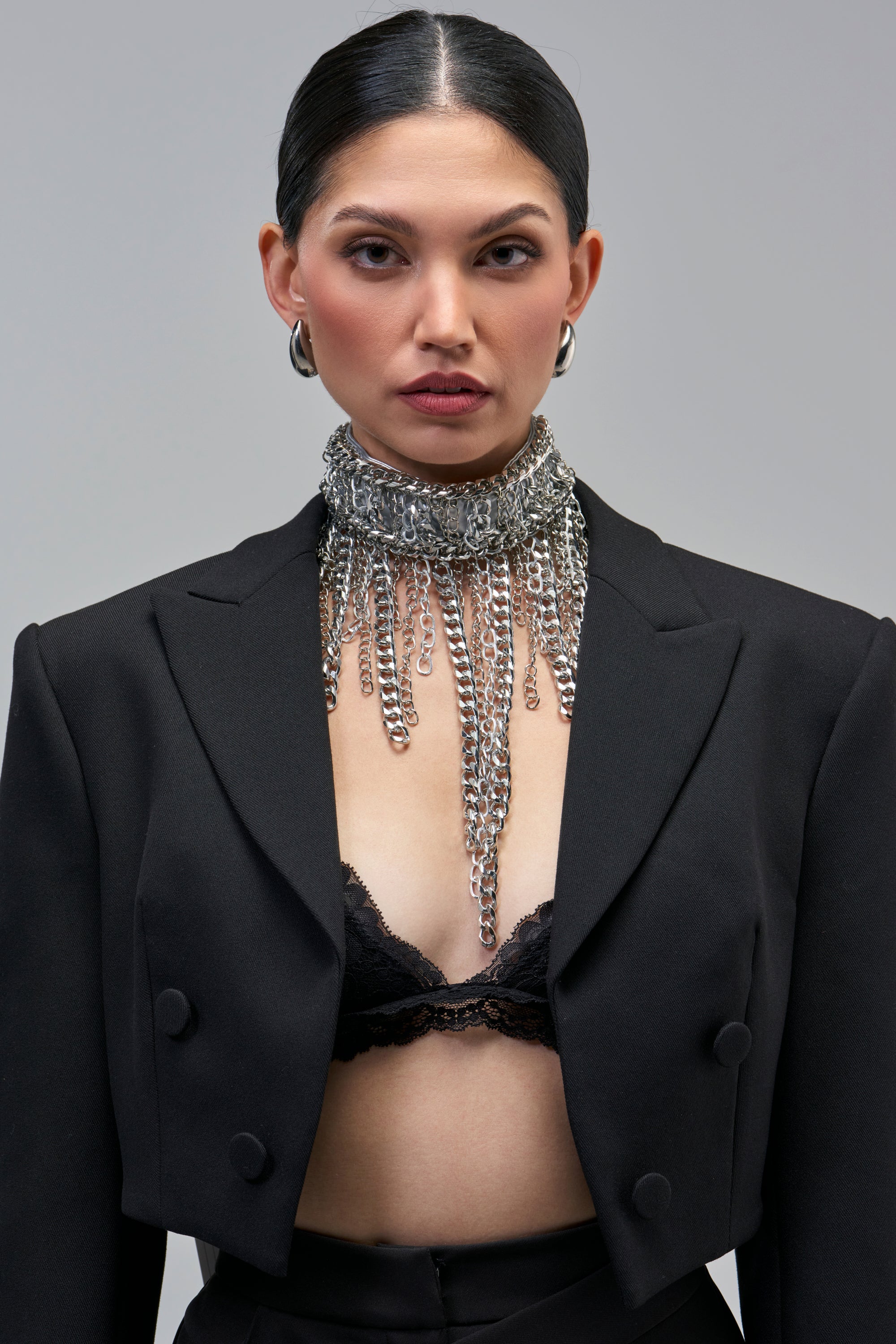 A person wearing a CHAINCORE CHOKER, a wide, silver-tone metal fringe necklace featuring layers of hanging chains.