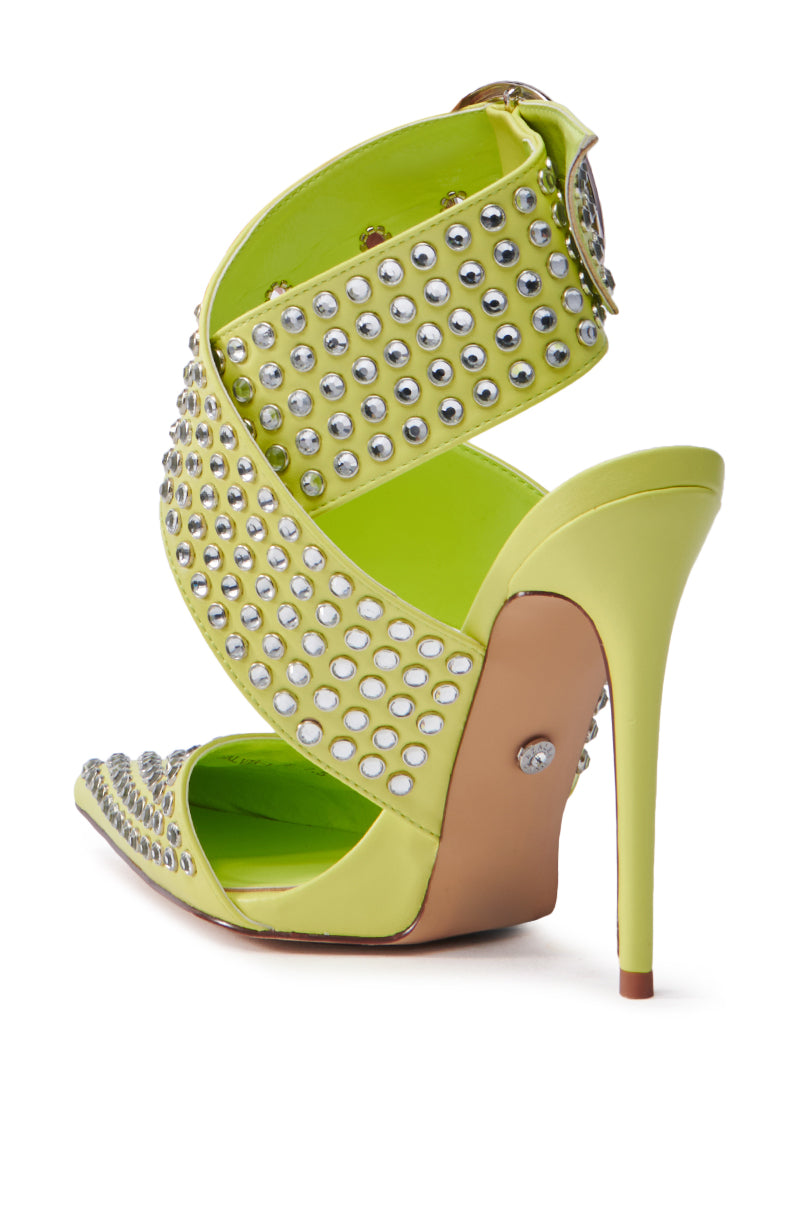 The AZALEA WANG SALVIA LIME STUDDED STILETTO PUMP features vibrant lime green faux leather with metallic studded crisscross ankle straps and a small decorative rivet on the stiletto heel, complemented by a tan-colored sole.