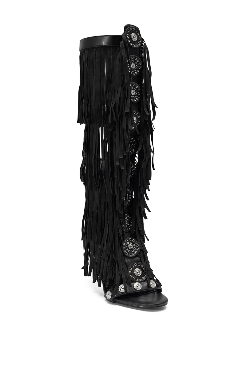 The AZALEA WANG SAMEYANA Black Fringe and Metal Stiletto Gladiator Sandal is a knee-high, open-toe heel with layered black fringe, silver studs, and decorative circular patterns.