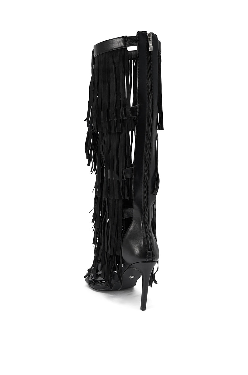 The AZALEA WANG SAMEYANA Black Fringe and Metal Stiletto Gladiator Sandal features long, layered fringe and a visible side zipper on a striking stiletto heel, shown from the back and slightly to the side against a white background.