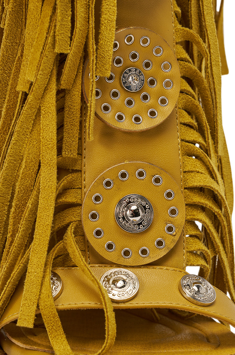 Close-up of the AZALEA WANG SAMEYANA Mustard Fringe and Metal Stiletto Gladiator Sandal, featuring yellow suede with fringe, silver studs, and ornate metal buttons that add bold bohemian-western flair. 6
