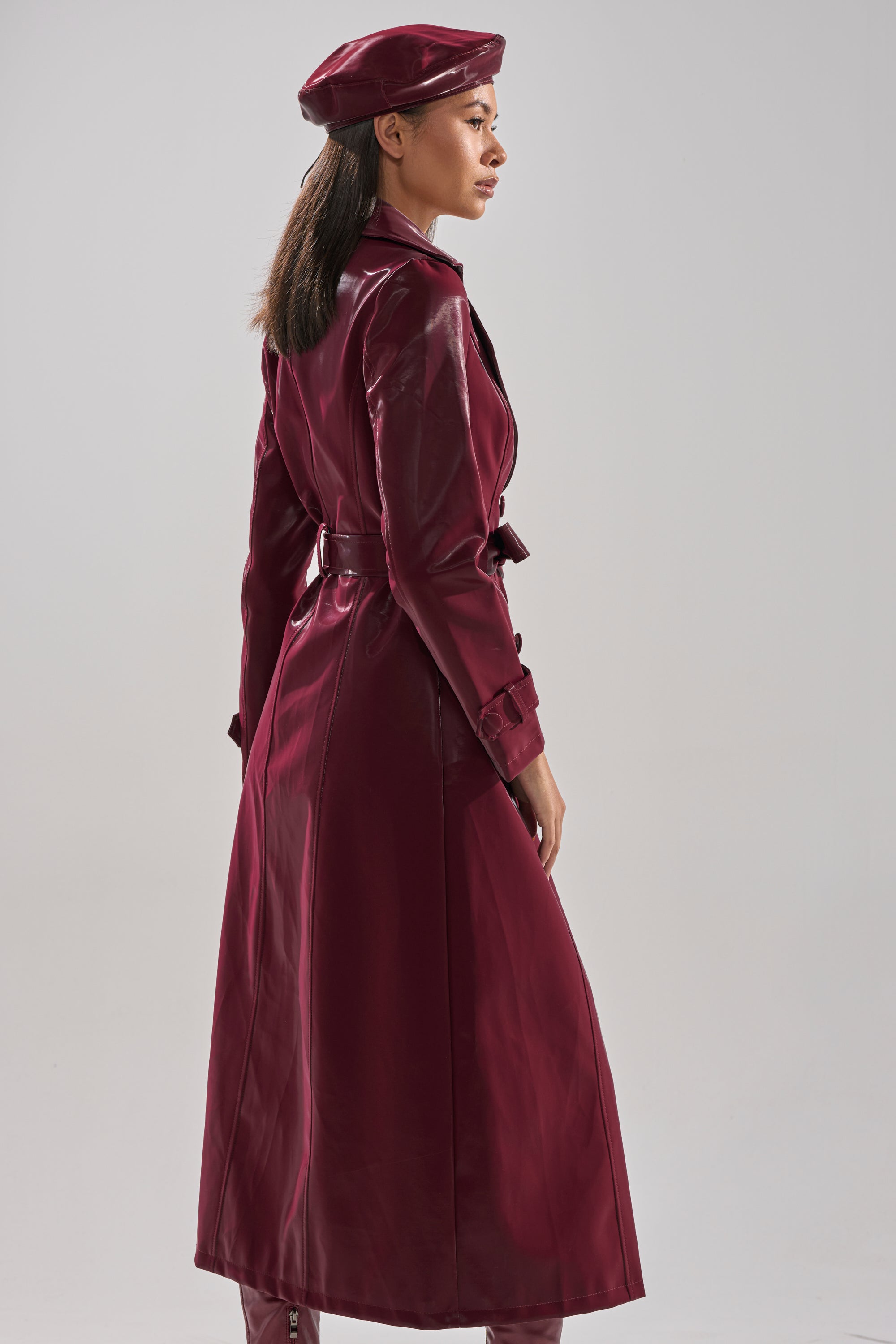 Wearing the SANDO LIQUID VELVET TRENCH IN BURGUNDY, she stands out as her striking outerwear captures every gaze.
