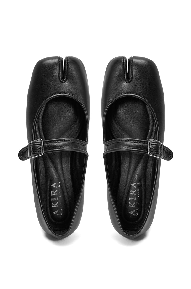 The AKIRA GOLD SANG BLACK PU SPLIT TOE FLAT is a pair of black faux leather Mary Jane shoes with buckled straps, a split square toe design, and a comfort cushion insole labeled "AKIRA," shown from above. 4