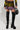 Wearing the TOO HOT TO HANDLE EMBELLISHED MINI SKIRT and a matching top adorned with vibrant colors, sequins, and rhinestones, the person holds a black studded handbag. They complete their look with knee-high black faux leather platform boots featuring buckles and zippers.