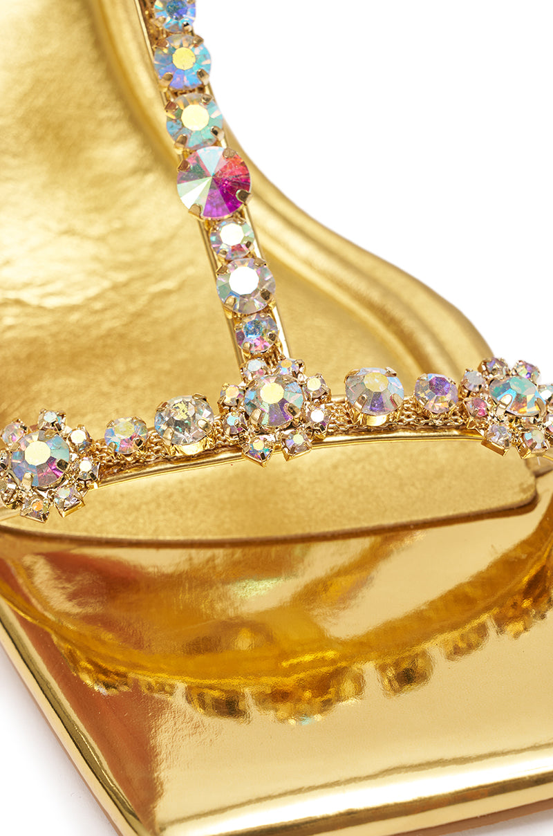 Close-up of the AZALEA WANG SCHANTELLE GOLD EMBELLISHED UPPER WEDGE SANDAL, featuring a metallic gold finish and sparkling iridescent rhinestones on the T-strap. 6