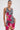A woman wears the WILD THANG PRINTED MINI DRESS, featuring a zebra print with bold pink tropical flowers, hoop earrings, and her hair pulled back, standing against a plain white background.