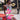 A woman in the WILD THANG PRINTED MINI DRESS with a bold zebra and pink floral print plus a wide gold belt sits on a red picnic bench. Behind her, a mural reads “WE BUILT Gold! SINCE 1969” with an arrow pointing right.