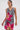 A woman models the WILD THANG PRINTED MINI DRESS, featuring a bold zebra print with large tropical flowers. She stands against a plain white background, wearing hoop earrings and her hair pulled back.